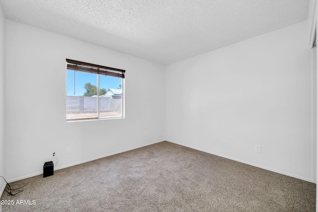 carpeted spare room featuring a textured ceiling and baseboards
