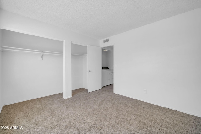 unfurnished bedroom featuring a textured ceiling, visible vents, multiple closets, carpet, and washer and clothes dryer