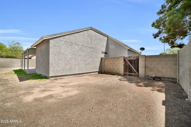 back of house with fence, a gate, and stucco siding