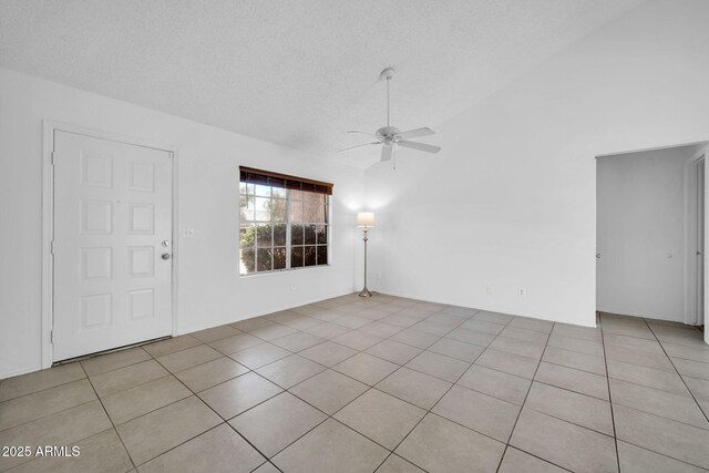 spare room with a textured ceiling, ceiling fan, light tile patterned flooring, and high vaulted ceiling