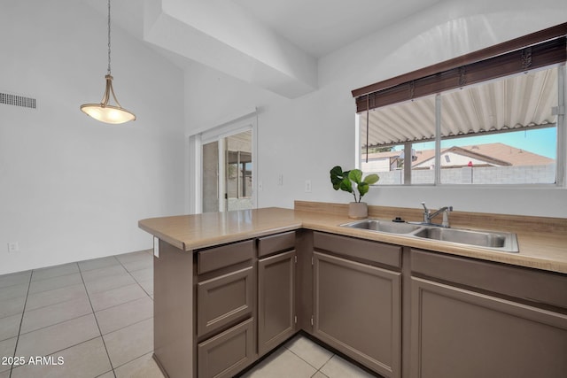 kitchen featuring a sink, gray cabinets, a peninsula, light tile patterned floors, and visible vents