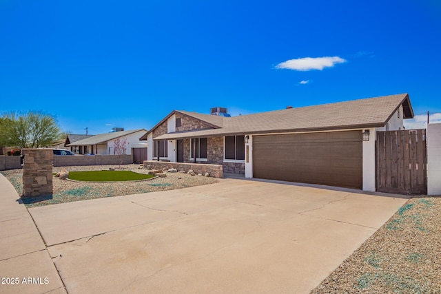 view of front of house featuring concrete driveway, an attached garage, fence, and stone siding