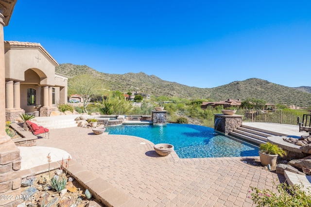 view of swimming pool with pool water feature, a mountain view, a patio area, and an in ground hot tub