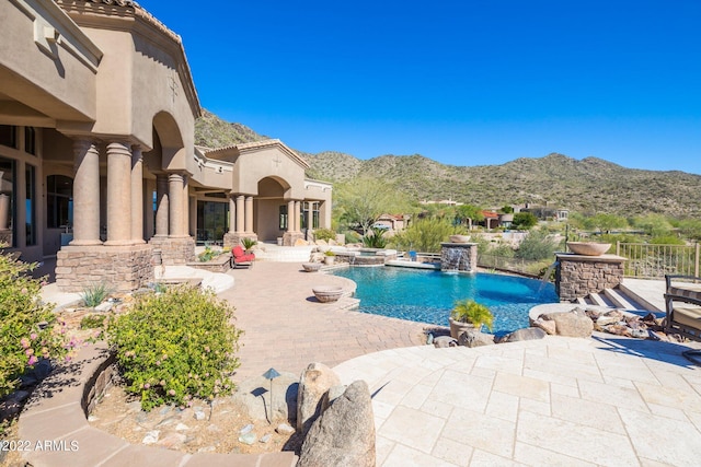 view of swimming pool with a patio area, a mountain view, and pool water feature