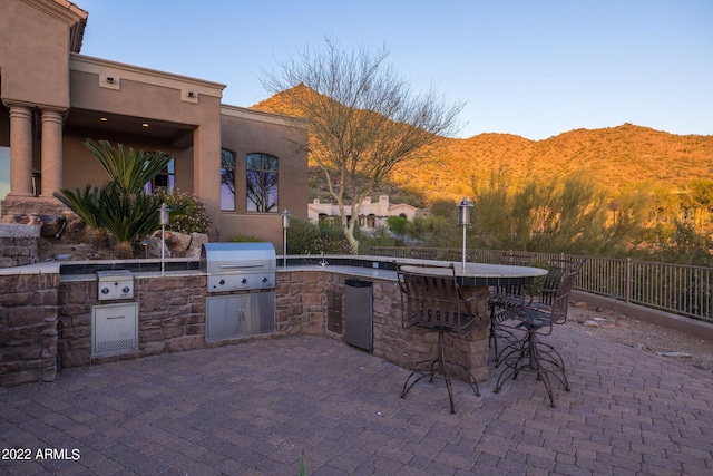 view of patio featuring a mountain view, a bar, area for grilling, and a grill