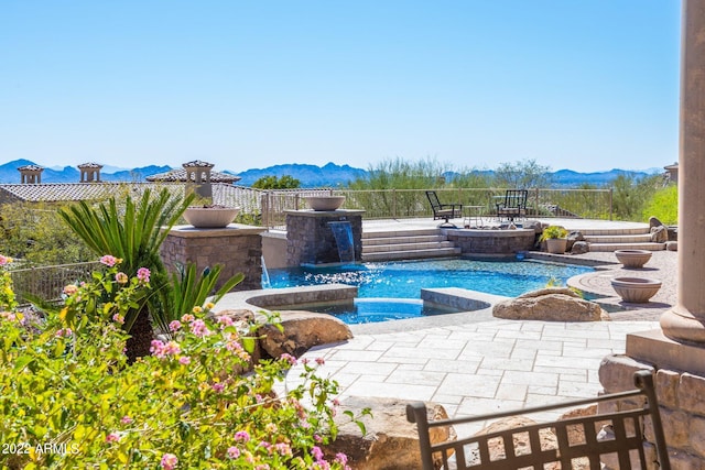 view of pool featuring pool water feature, a mountain view, and an in ground hot tub