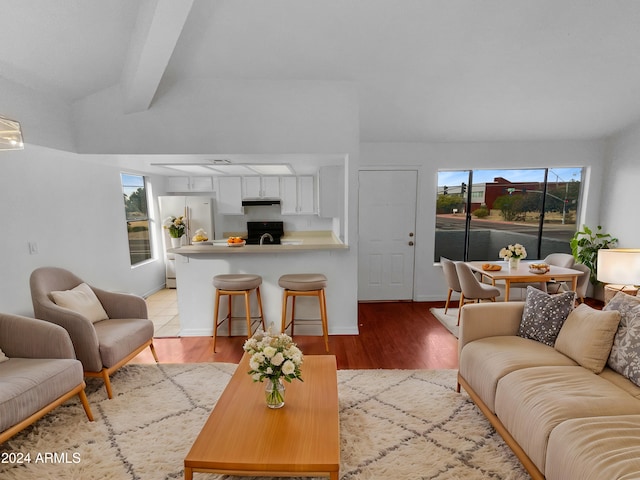 living room featuring beamed ceiling and light hardwood / wood-style flooring