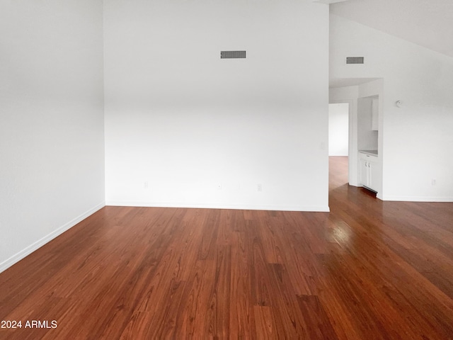 empty room with dark wood-type flooring and vaulted ceiling