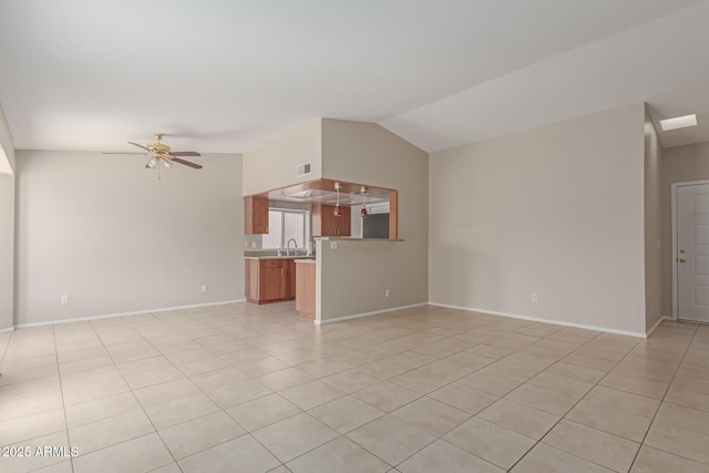 unfurnished living room with ceiling fan, sink, light tile patterned flooring, and lofted ceiling