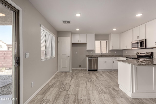 kitchen featuring white cabinets, dark stone counters, and appliances with stainless steel finishes