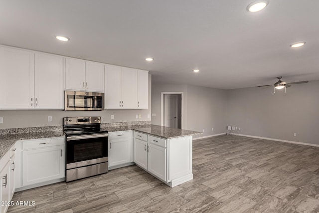 kitchen with stainless steel appliances, white cabinetry, ceiling fan, kitchen peninsula, and dark stone counters