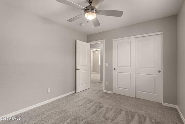 unfurnished bedroom with ceiling fan, a closet, and light carpet