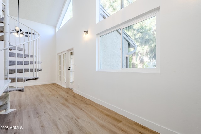 foyer entrance with ceiling fan, french doors, high vaulted ceiling, and wood-type flooring