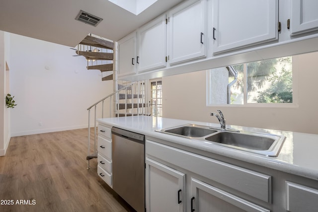 kitchen featuring white cabinetry, sink, stainless steel dishwasher, and light hardwood / wood-style flooring