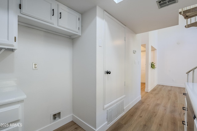 laundry room with light hardwood / wood-style floors and cabinets