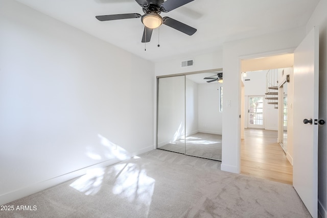 unfurnished bedroom with ceiling fan, light carpet, and a closet