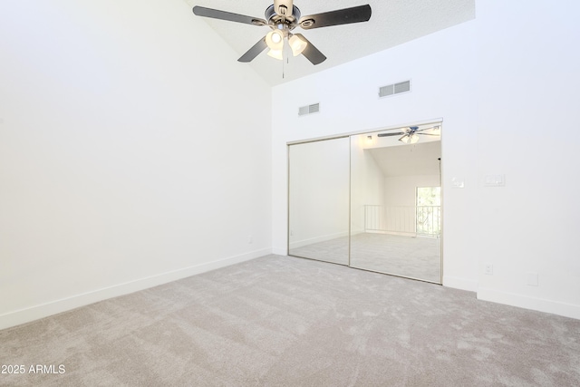 unfurnished bedroom with ceiling fan, light colored carpet, high vaulted ceiling, and a closet