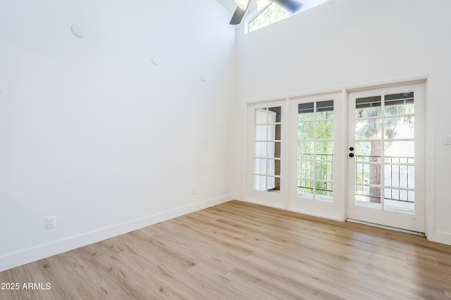 interior space featuring ceiling fan, a towering ceiling, and light wood-type flooring