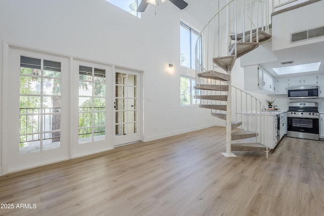 interior space featuring plenty of natural light, a towering ceiling, and light hardwood / wood-style floors