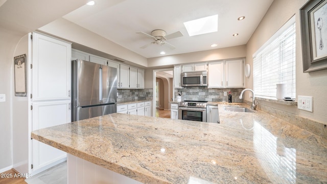 kitchen featuring stainless steel appliances, sink, white cabinets, and kitchen peninsula