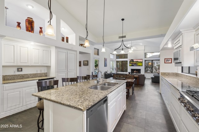 kitchen featuring stainless steel appliances, white cabinetry, sink, and a center island with sink