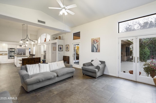 tiled living room with french doors, sink, ceiling fan with notable chandelier, and high vaulted ceiling