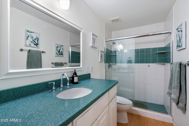 bathroom featuring a shower with door, vanity, and toilet