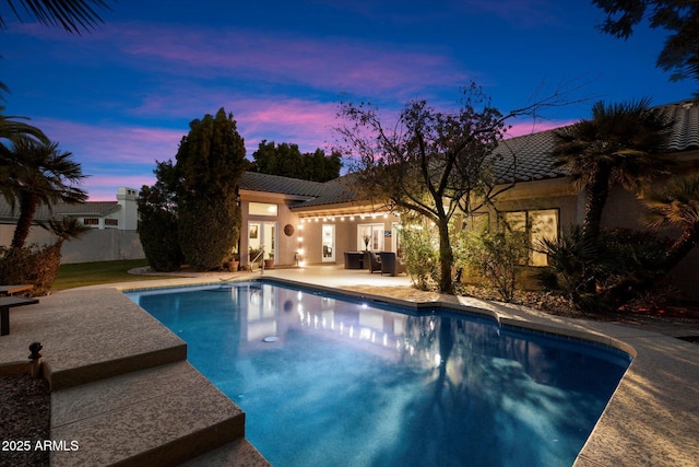 pool at dusk featuring a patio area