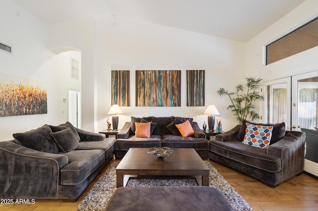 living room with french doors, high vaulted ceiling, and hardwood / wood-style floors