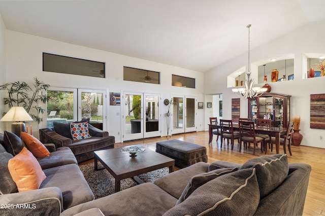 living room featuring a notable chandelier, light hardwood / wood-style floors, french doors, and high vaulted ceiling