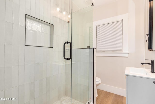 bathroom with vanity, wood-type flooring, a shower with door, and toilet