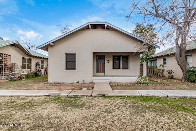 bungalow-style house featuring covered porch and a front lawn