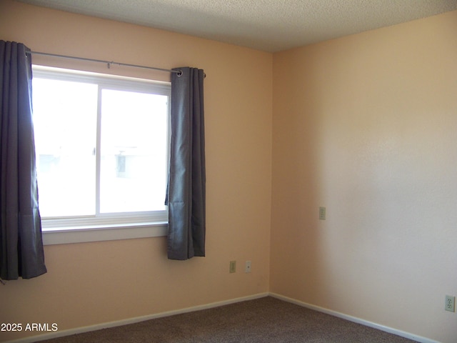 spare room featuring carpet flooring, a textured ceiling, and baseboards