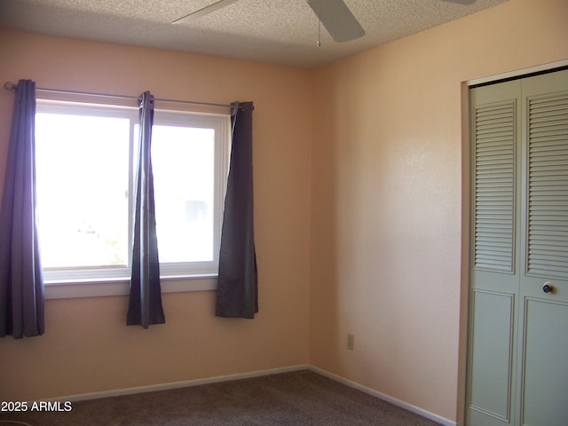 empty room featuring ceiling fan, carpet, baseboards, and a textured ceiling