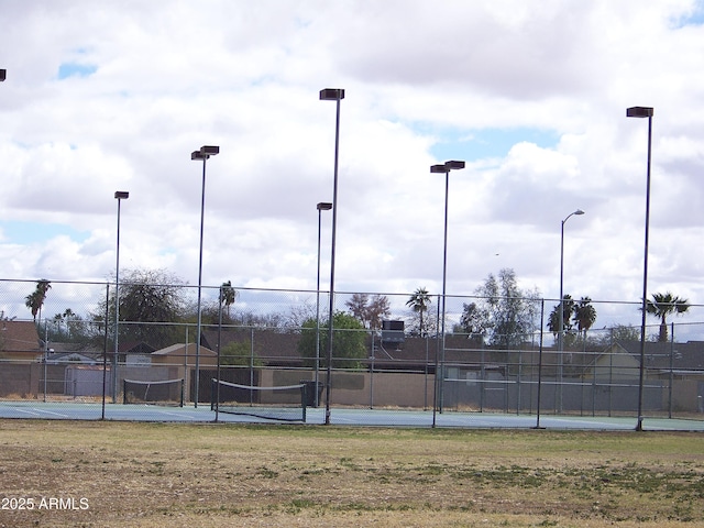 view of tennis court featuring fence and a lawn