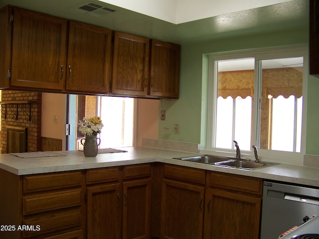 kitchen featuring visible vents, a peninsula, a sink, light countertops, and dishwasher