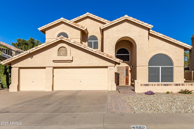 mediterranean / spanish-style home featuring a tiled roof, concrete driveway, and stucco siding