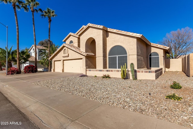 mediterranean / spanish house with concrete driveway, an attached garage, a tile roof, and stucco siding