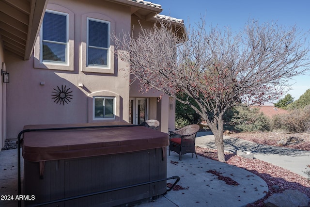 view of side of property featuring a patio and a hot tub