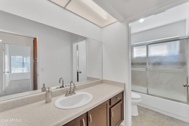 full bathroom featuring vanity, combined bath / shower with glass door, toilet, and tile patterned floors