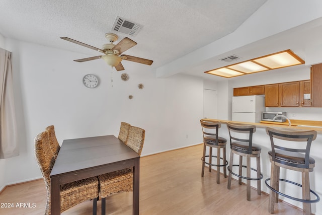 dining space featuring ceiling fan, a textured ceiling, and light hardwood / wood-style flooring