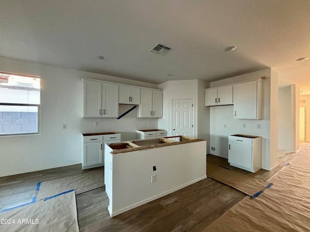 kitchen featuring hardwood / wood-style flooring, a kitchen island, and white cabinets