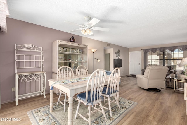 dining room with ceiling fan, wood-type flooring, and a textured ceiling