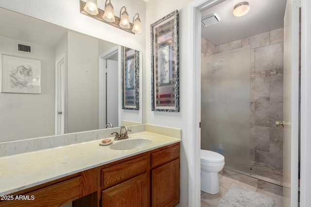 bathroom with tile patterned flooring, vanity, tiled shower, and toilet