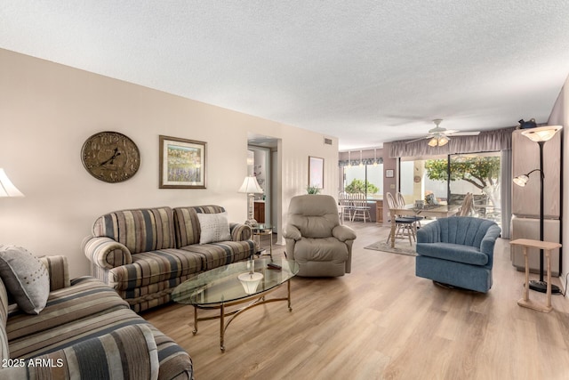 living room with ceiling fan, light hardwood / wood-style floors, and a textured ceiling