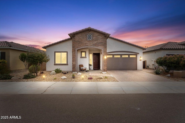 view of front of house with stone siding, a garage, driveway, and stucco siding