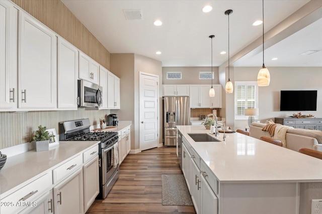 kitchen featuring visible vents, appliances with stainless steel finishes, open floor plan, and a sink