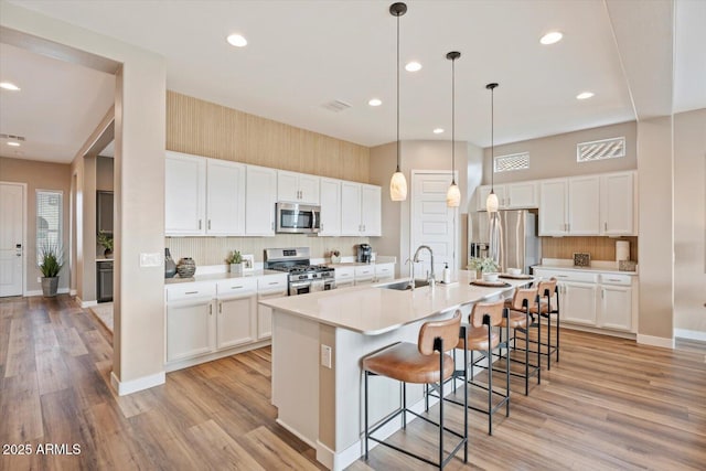 kitchen with a breakfast bar area, light wood finished floors, a sink, stainless steel appliances, and a large island