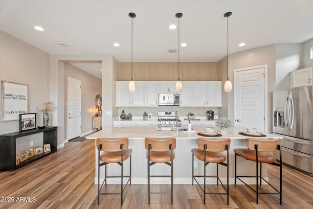 kitchen with backsplash, white cabinets, stainless steel fridge with ice dispenser, range, and white microwave