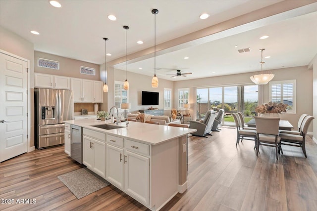 kitchen with visible vents, wood finished floors, white cabinets, stainless steel appliances, and a sink